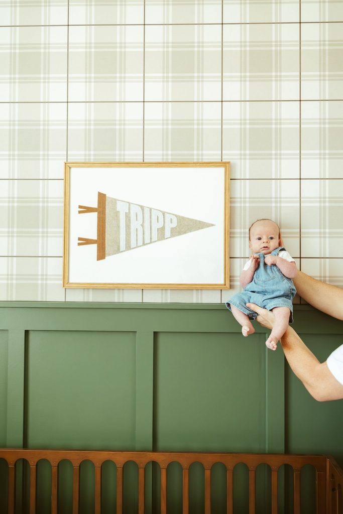 Gilbert newborn photography featuring a newborn baby lying in the nursery beside a personalized framed sign during an in-home session.