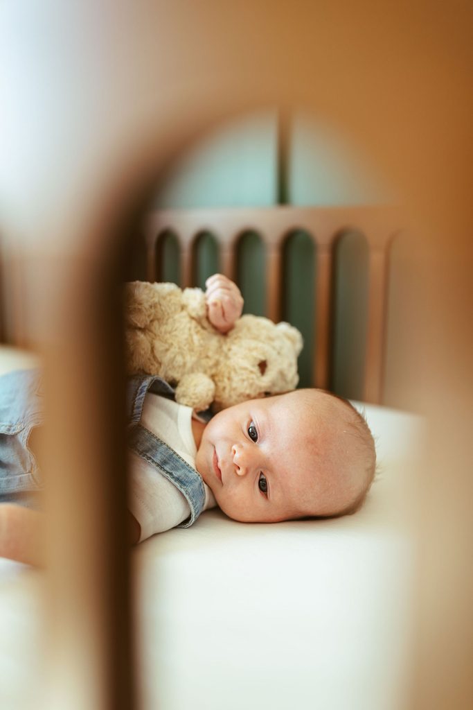 Gilbert newborn photographer capturing newborn siblings lying together on a bed during a beautiful in-home newborn session in Gilbert, Arizona.