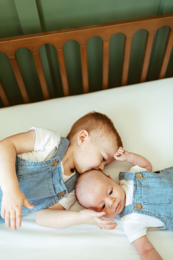Gilbert newborn photographer capturing a toddler gently kissing his newborn sibling on the cheek during an in-home newborn session in Gilbert, Arizona.