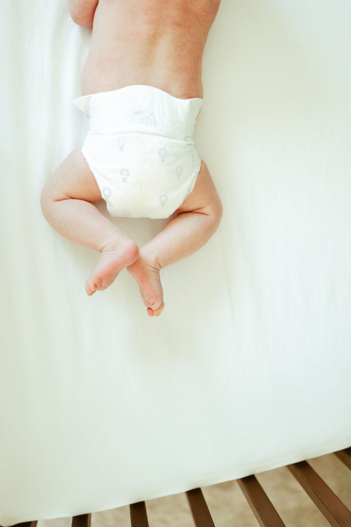 Close-up newborn photography of a baby's tiny crossed feet and legs during a relaxed in-home newborn session in Gilbert, Arizona.