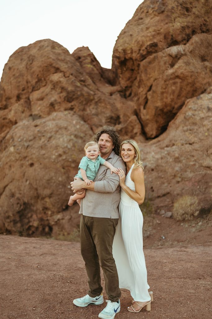 Mesa family photography showcasing a beautifully styled family of three standing on the desert trails during a sun-drenched evening session.