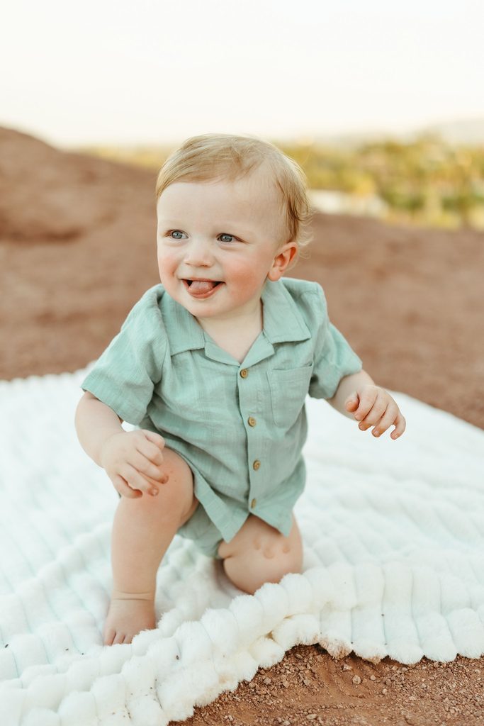 Arizona family photography featuring an unposed, playful milestone portrait of a baby boy crawling on a white knit blanket at Papago Park Hole in the Rock.