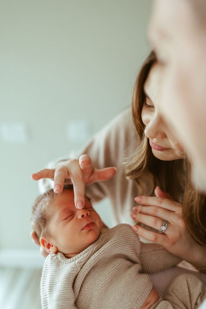 Gilbert newborn photography featuring a mother gently touching her baby's face during a natural in-home newborn photography session in the Phoenix area.