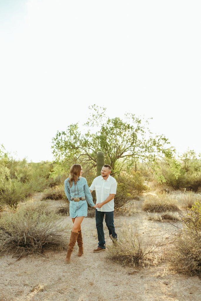 Arizona couples photographer capturing a couple sitting closely together on a blanket surrounded by desert trees and warm golden light.