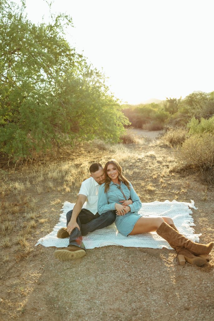 Superstition Mountains engagement session featuring a couple lying together on a blanket, sharing an intimate moment in the Arizona desert.