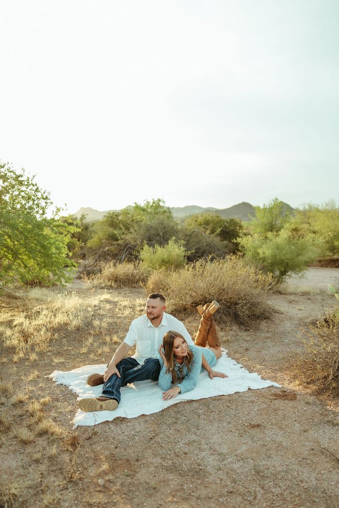 Superstition Mountains couples photographer capturing a couple relaxing together on a blanket in the Arizona desert during golden hour.