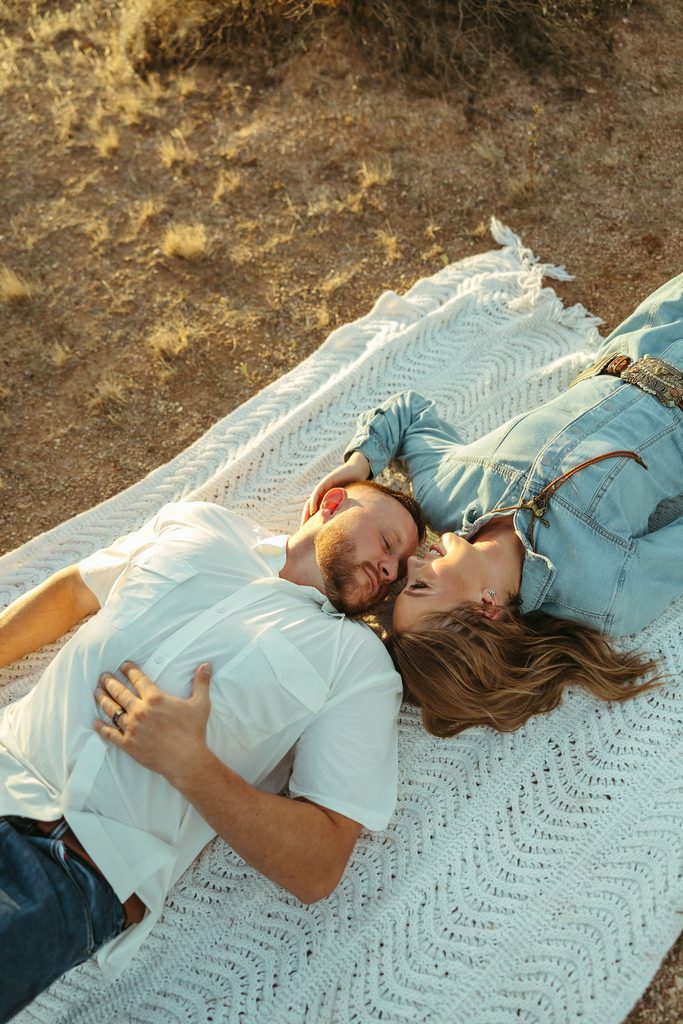 Arizona couples photography featuring a couple lying together on a cozy blanket surrounded by the Sonoran Desert landscape.