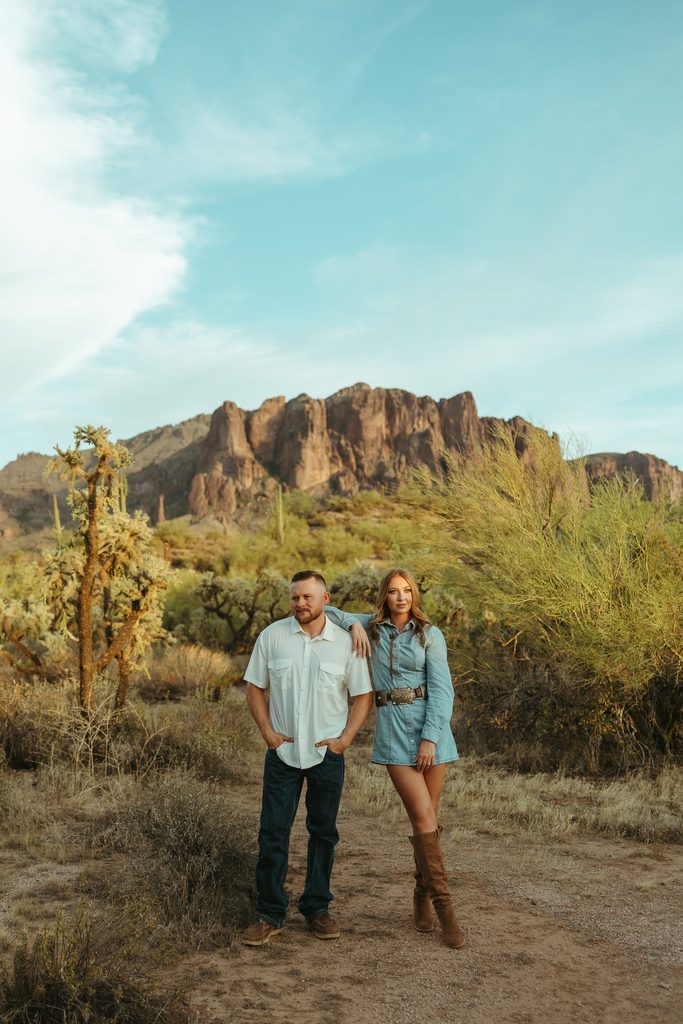 Arizona engagement photographer capturing a couple walking through the desert with the dramatic Superstition Mountains behind them.