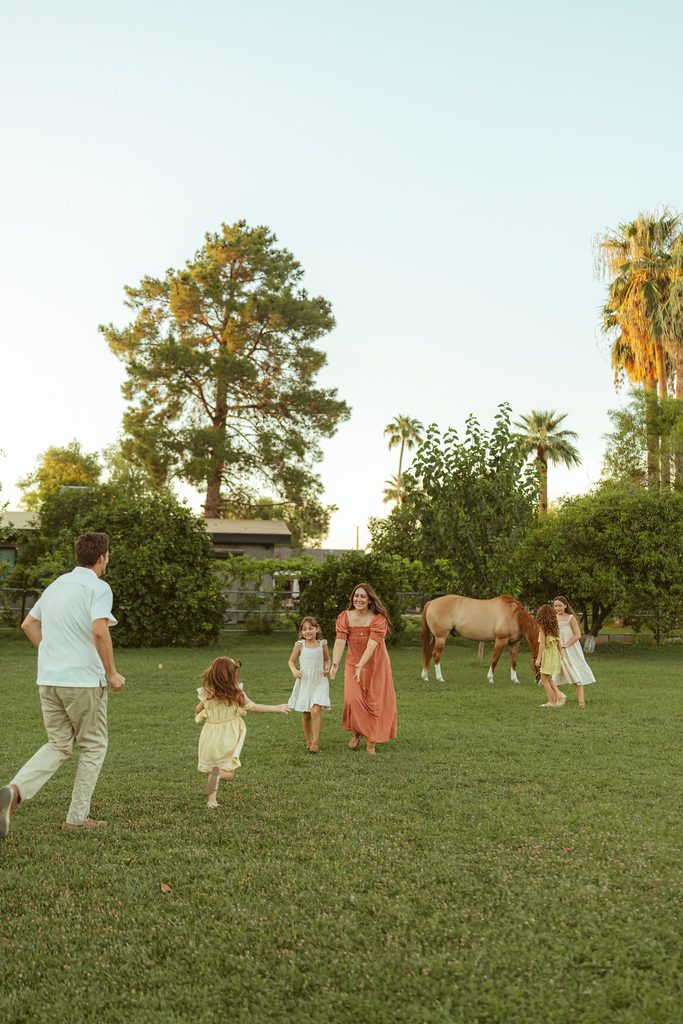 Gilbert family photographer capturing parents and children running together through the pasture during a relaxed family photography session at Floyd Family Farms.