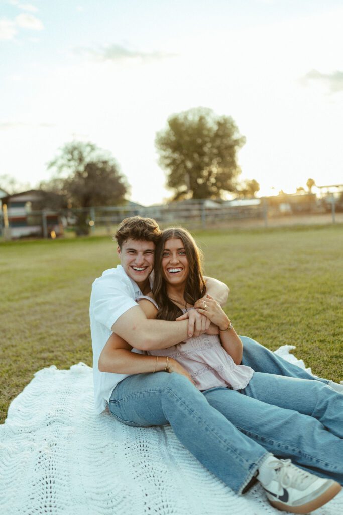 Couple sitting together on a blanket during a golden hour couples photo session in Gilbert, Arizona