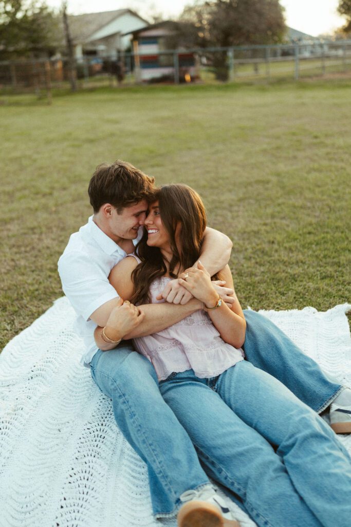 Couple cuddling and laughing on a blanket during a candid couples photo session at The Cozy Acre in Gilbert, AZ