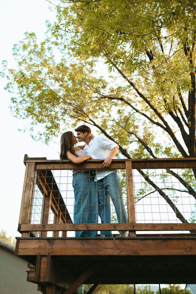 Couple kissing on a wooden deck during romantic outdoor couples photos at The Cozy Acre in Gilbert, AZ