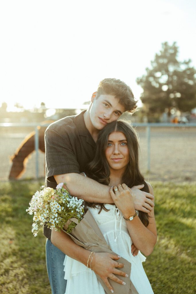 Couple posing with flowers during an outdoor photography session at The Cozy Acre in Gilbert, AZ