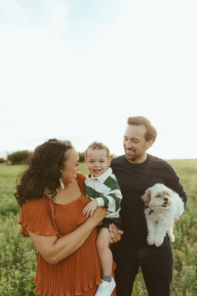 Family of three laughing together during an outdoor Queen Creek family photo session