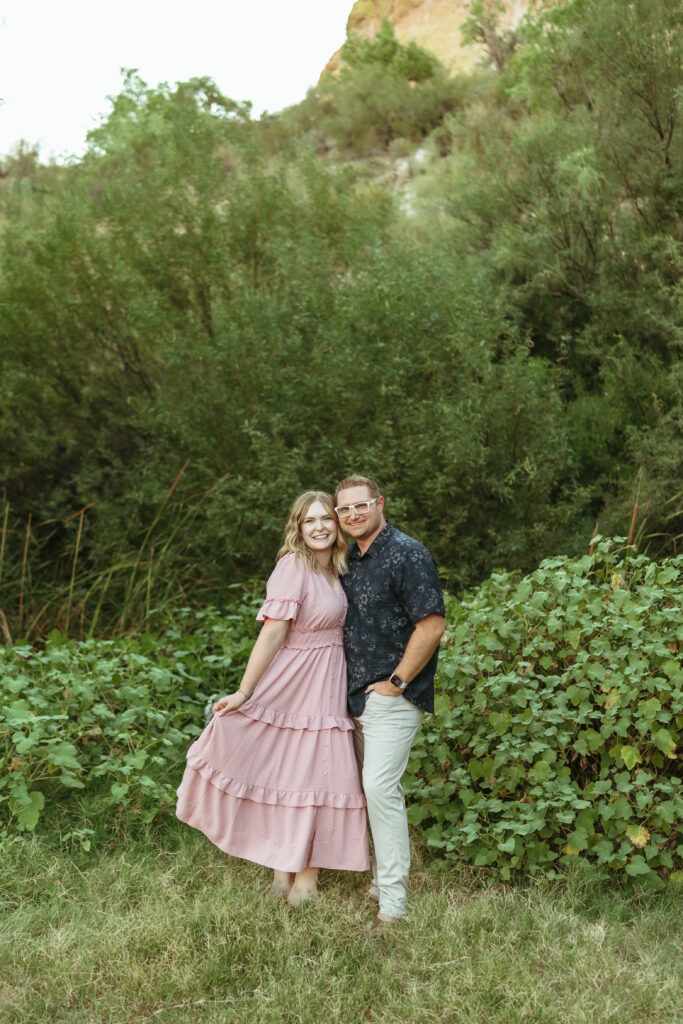 Couple smiling together surrounded by lush greenery during a family photography session at Butcher Jones in Mesa, Arizona.
